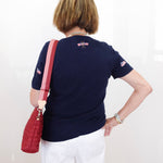 Person wearing a navy blue shirt with a red bag over their shoulder against a white background