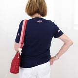 Person wearing a navy blue shirt with a red bag over their shoulder against a white background