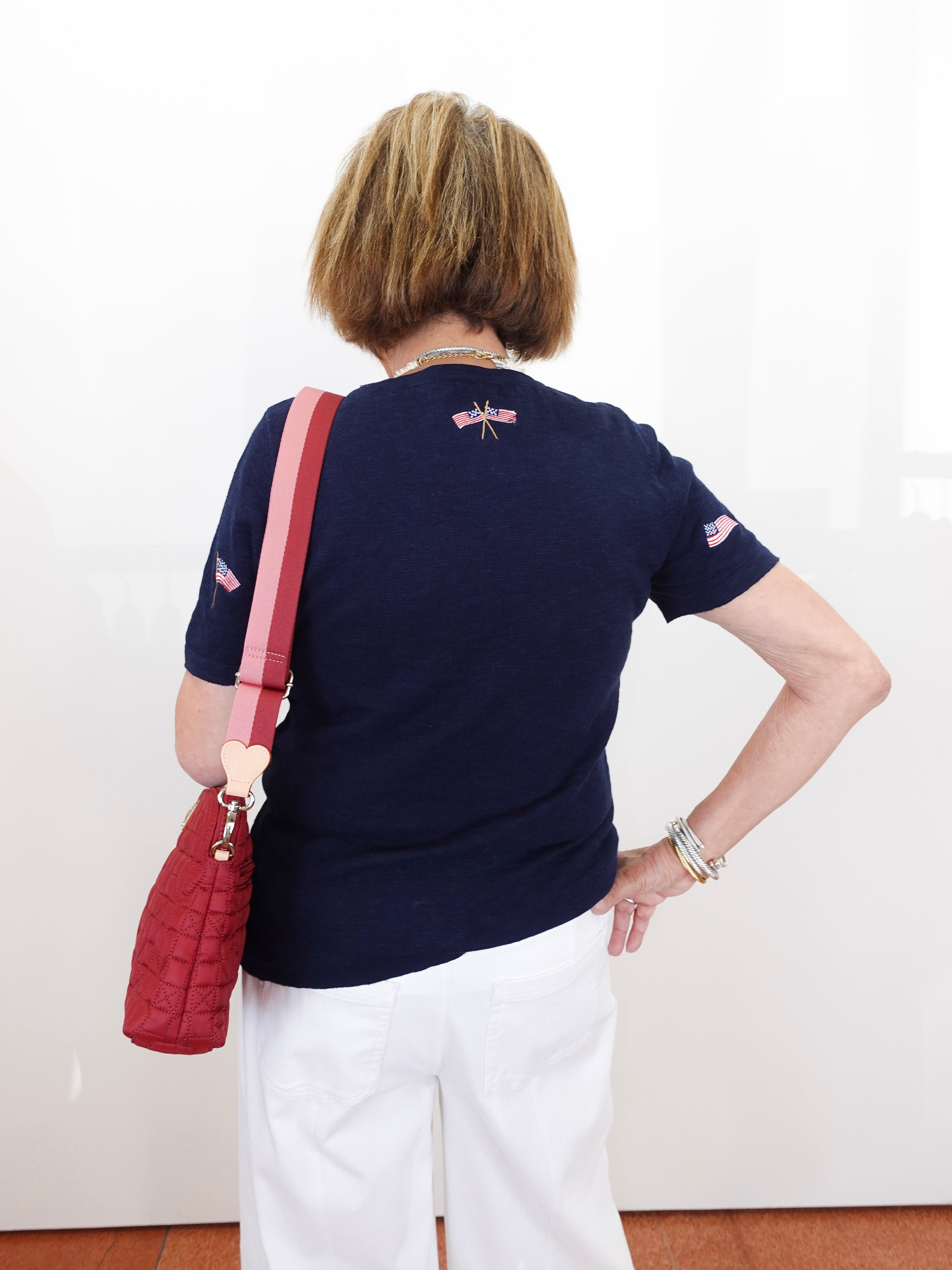 Person wearing a navy blue shirt with a red bag over their shoulder against a white background