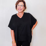 Woman wearing a black outfit with glasses against a white background