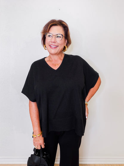 Woman wearing a black outfit with glasses against a white background