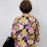 Person wearing a floral blouse with a plain background