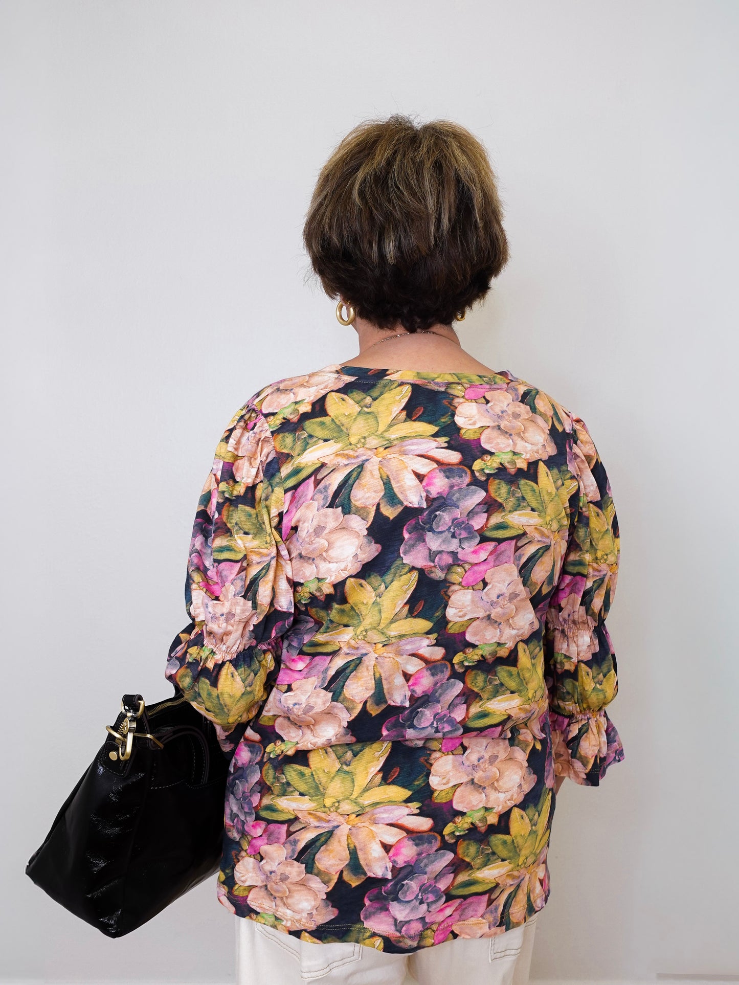 Person wearing a floral blouse with a plain background