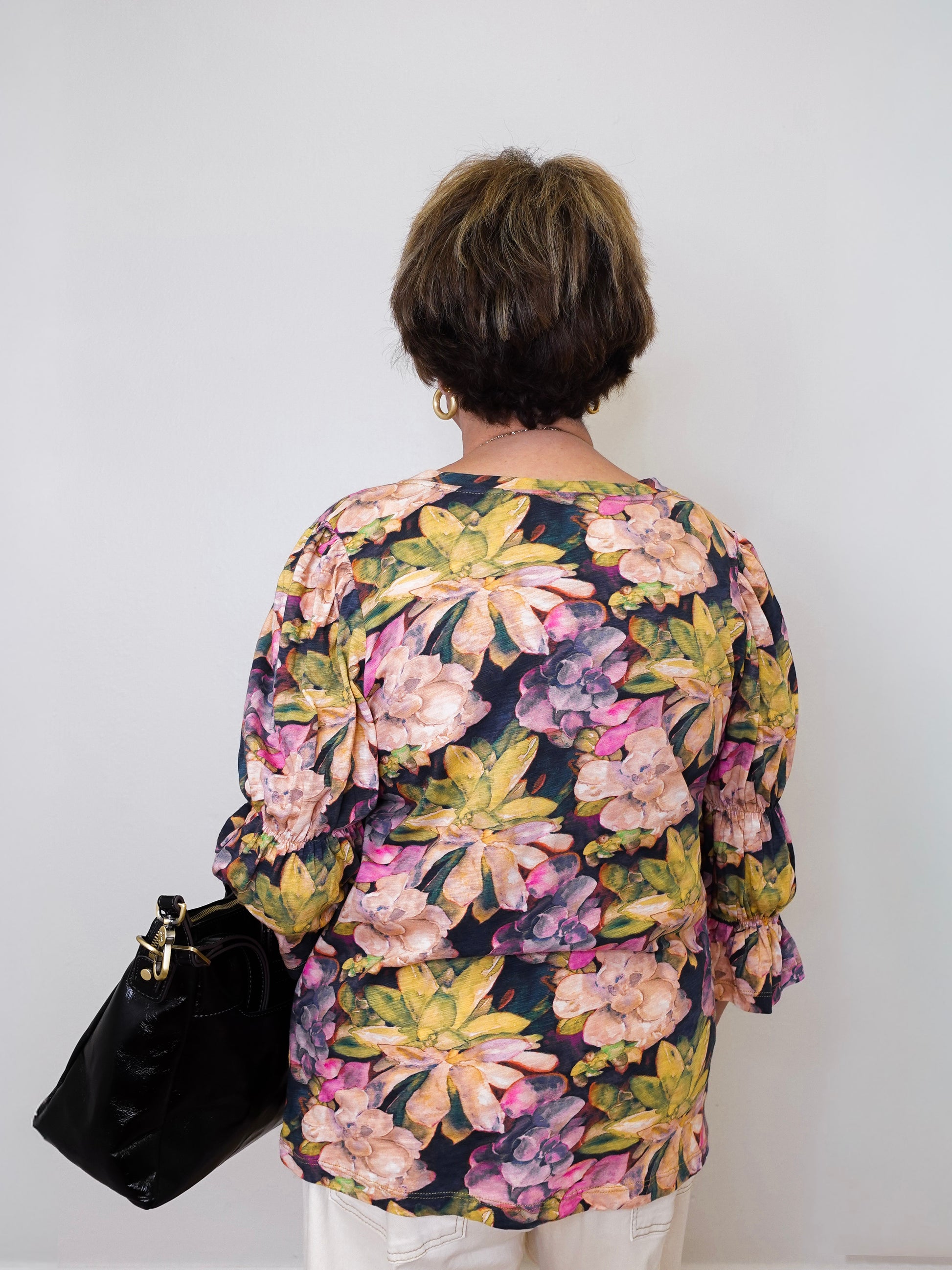 Person wearing a floral blouse with a plain background