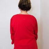 Person wearing a red shirt standing against a white wall