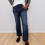 Person wearing blue jeans and a white top against a plain background