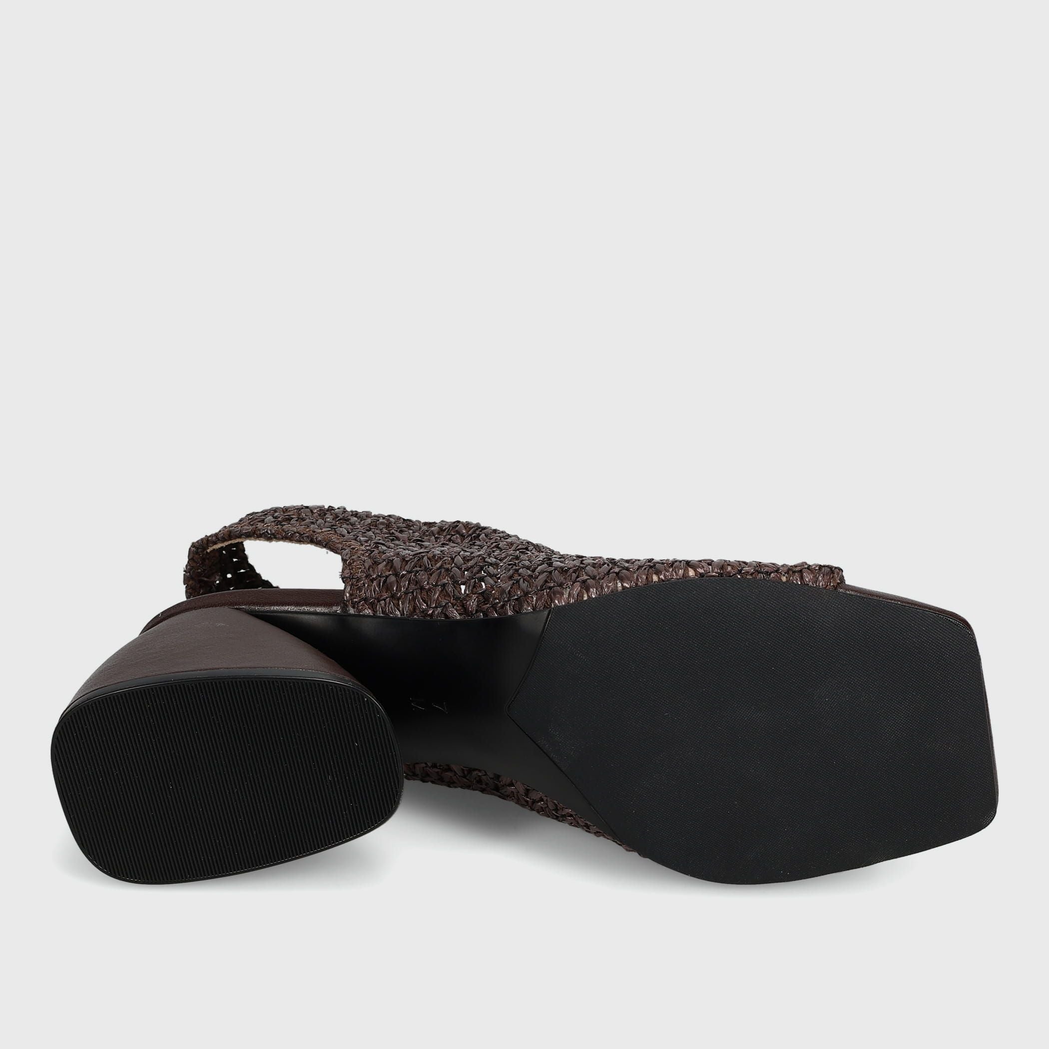A single women's flat shoe shown from a side angle, featuring a dark brown woven strap and a black block heel with a black sole, set against a light gray background.