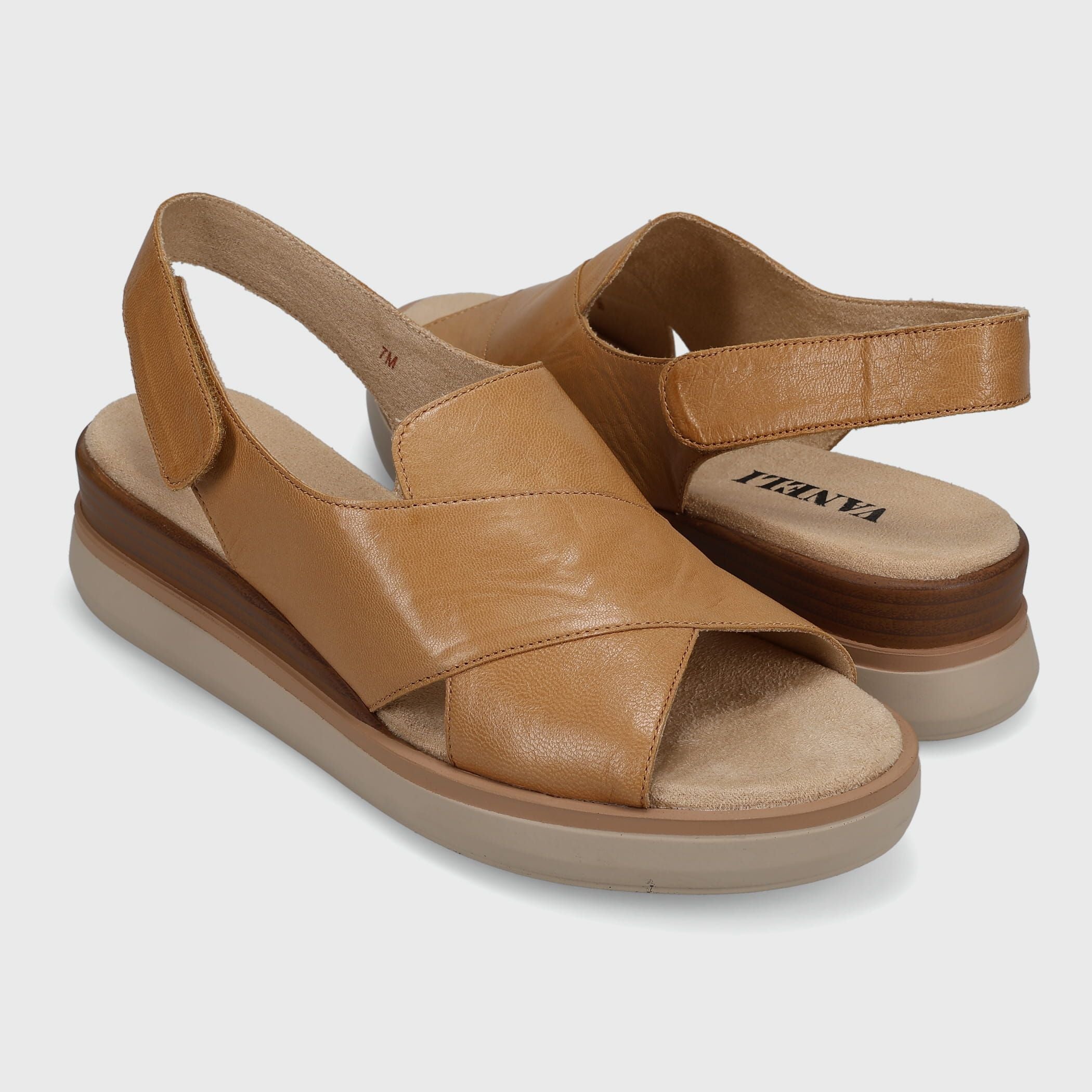 Pair of tan sandals on a light gray background