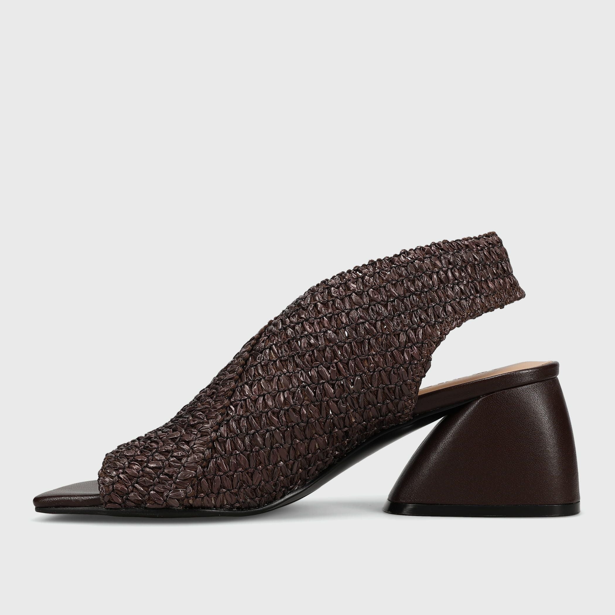 A dark brown woven slingback mule sandal with a chunky geometric block heel, shown from a side profile on a light gray background.