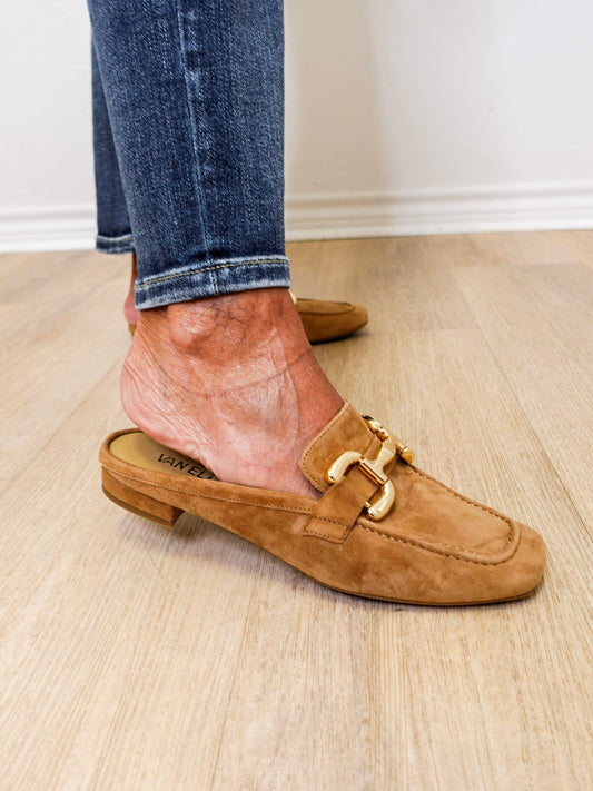 Brown suede loafer worn with rolled-up jeans on a wooden floor.