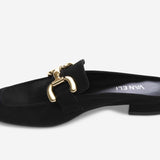 Black slip-on shoe with gold buckle on a white background