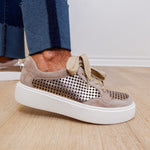 Beige sneaker with perforated design on a wooden floor