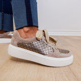 Beige sneaker with perforated design on a wooden floor