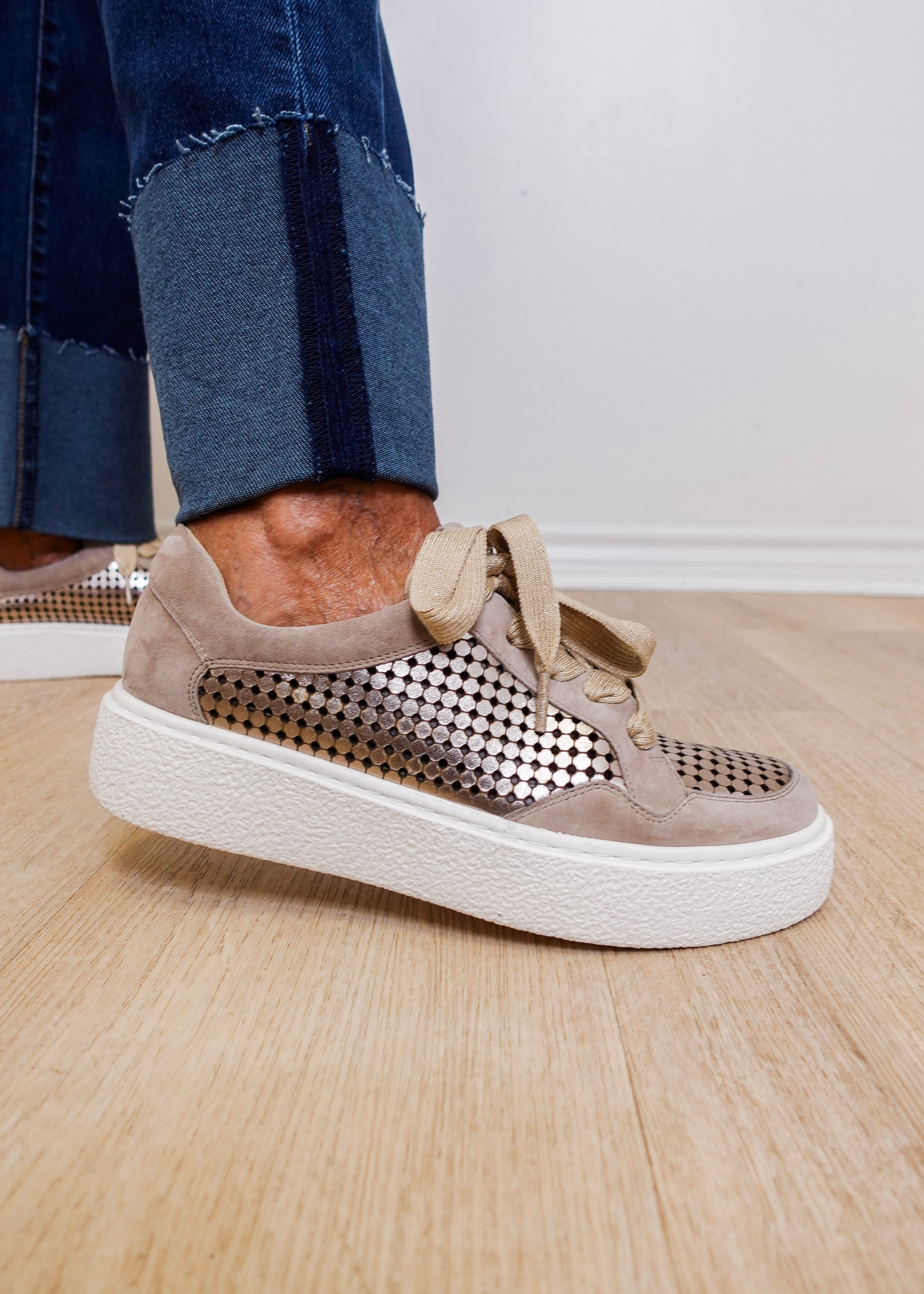 Beige sneaker with perforated design on a wooden floor