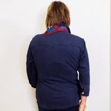 Woman wearing a leather shirt jacket against a white wall. 