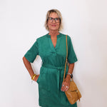 Woman wearing a green dress with a brown bag against a white background