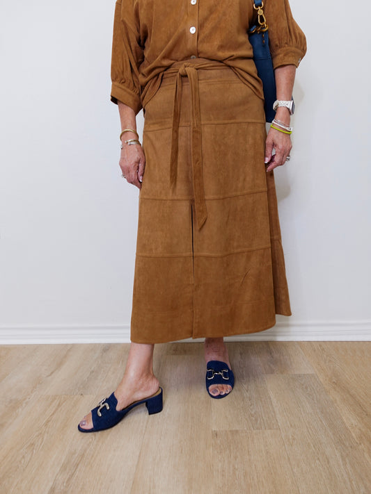 Person wearing a brown skirt with a white wall background