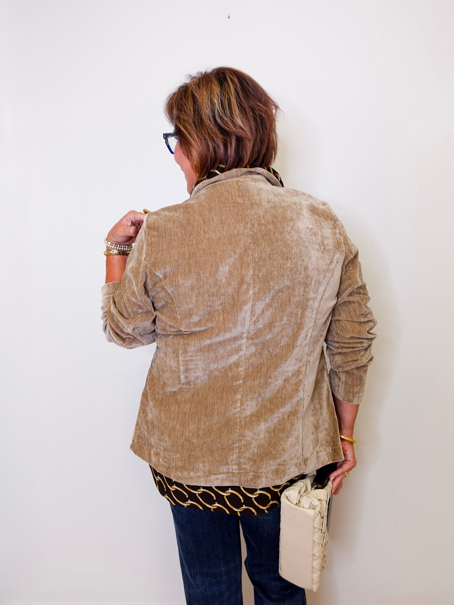 Person wearing a beige jacket against a white wall