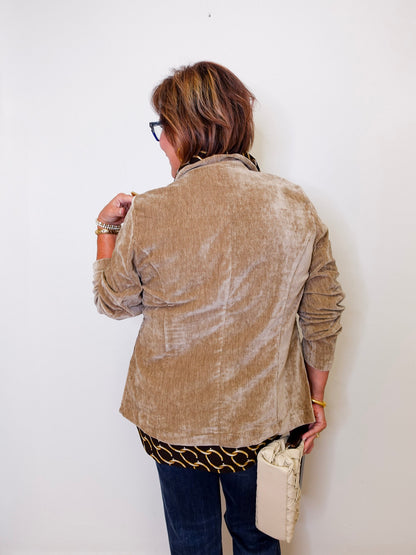 Person wearing a beige jacket against a white wall