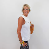 Woman wearing a white sleeveless top and patterned skirt against a plain background