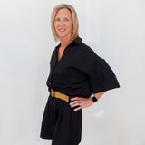 Woman wearing a black dress with a belt against a white background