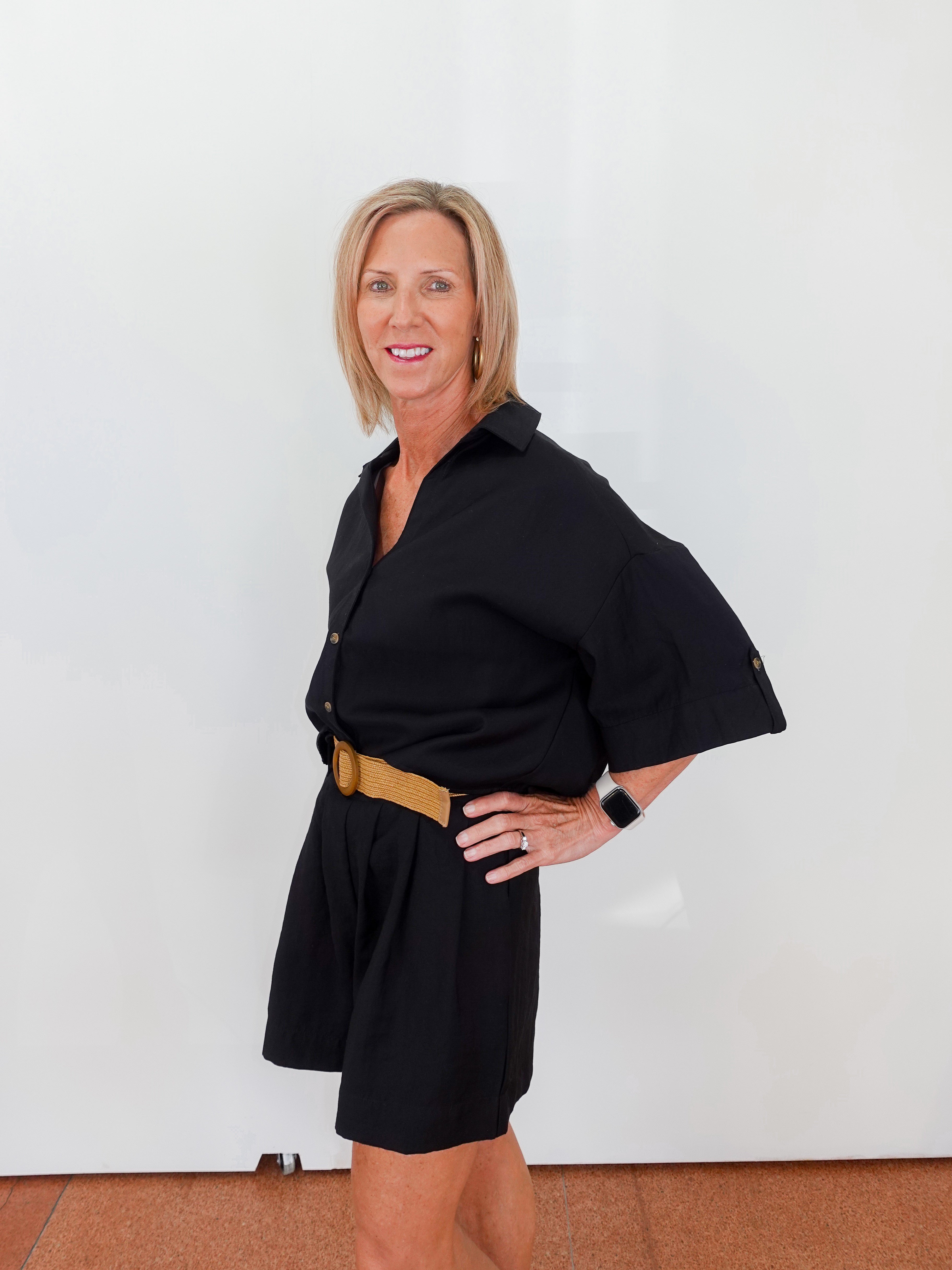 Woman wearing a black dress with a belt against a white background