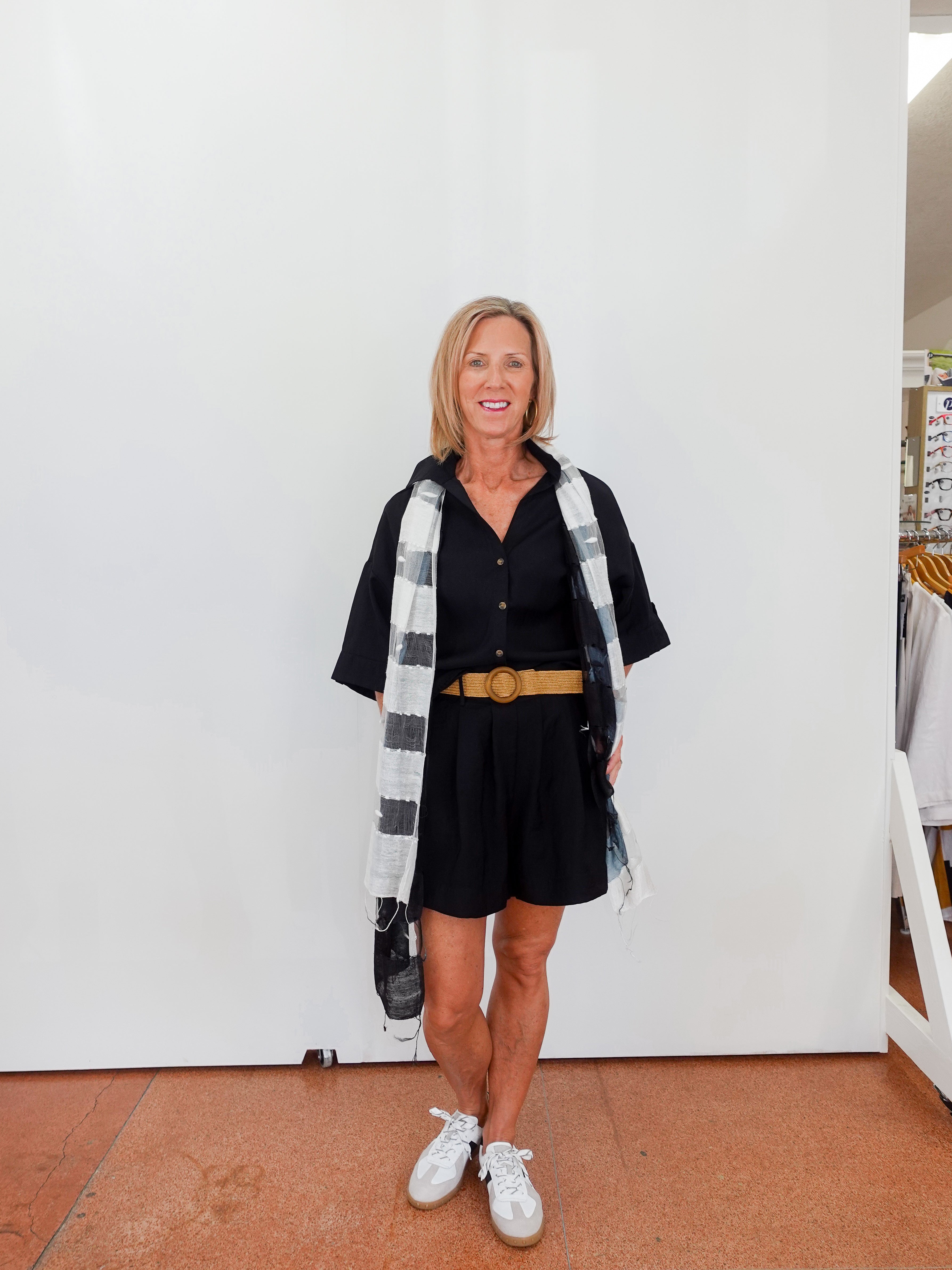 Woman wearing a black outfit with a plaid scarf in a store setting