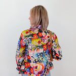 Person wearing a colorful floral jacket against a white background
