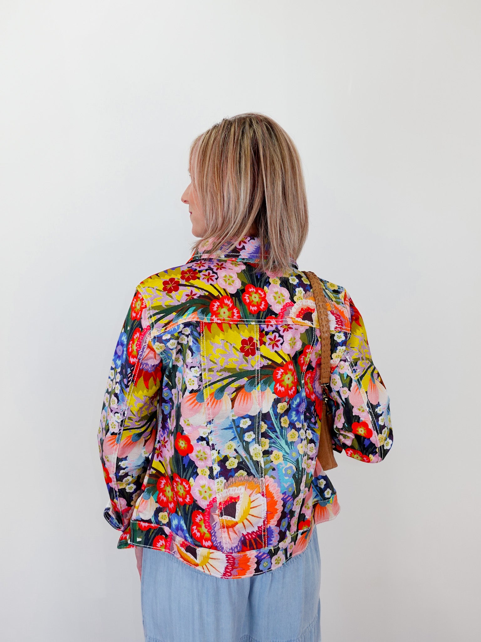 Person wearing a colorful floral jacket against a white background