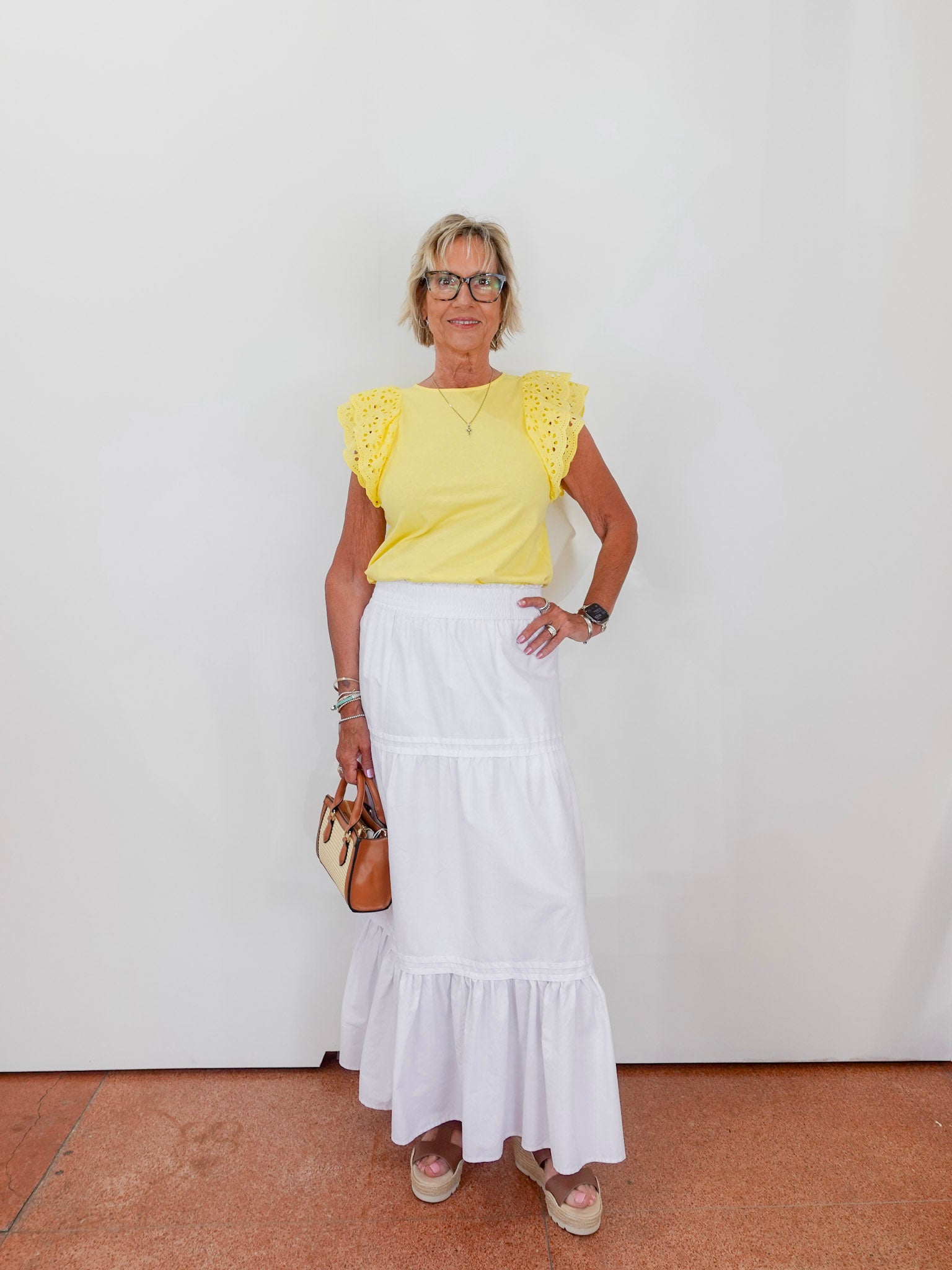Woman wearing a yellow top and white skirt against a plain background