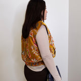 Person wearing a patterned vest against a white wall