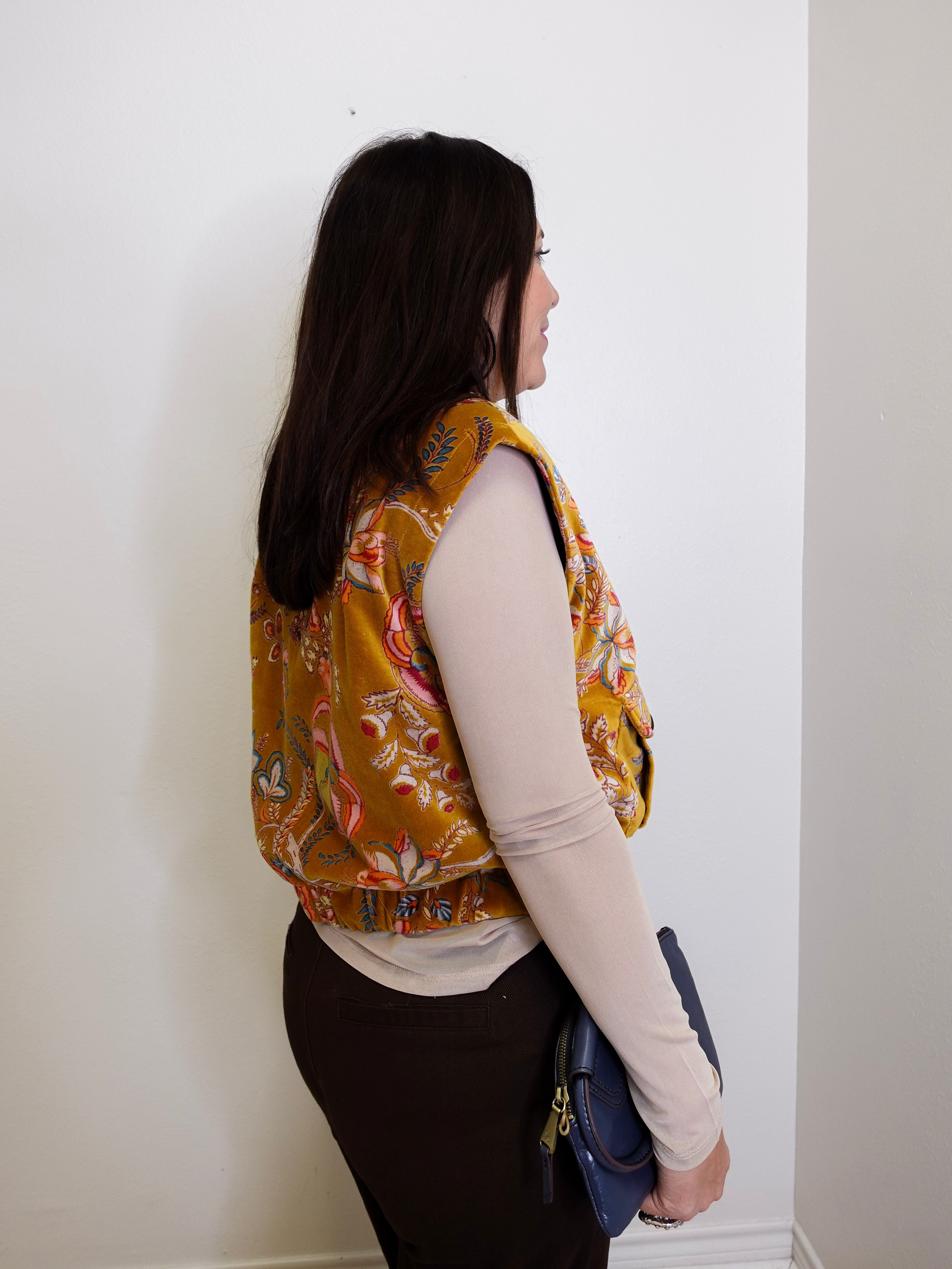 Person wearing a patterned vest against a white wall