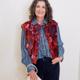 Woman wearing a colorful vest over a denim shirt with a white background