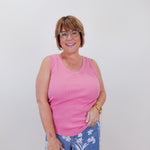 Woman wearing a pink tank top and blue floral pants against a white background