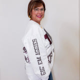Woman wearing a white sweatshirt with text and graphics, standing against a plain background