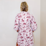 Person wearing a red and white patterned dress against a plain wall.