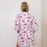 Person wearing a red and white patterned dress against a plain wall.