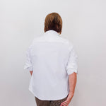 Person wearing a white shirt and patterned pants against a plain background