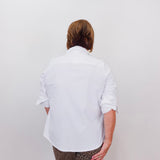 Person wearing a white shirt and patterned pants against a plain background