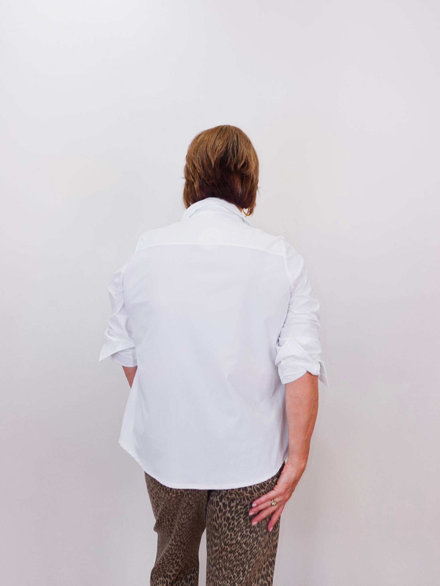 Person wearing a white shirt and patterned pants against a plain background