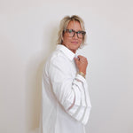 Woman wearing a white shirt and glasses against a plain background