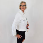 Woman wearing a white jacket and black shorts against a plain background