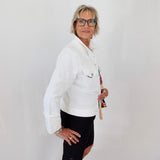 Woman wearing a white jacket and black shorts against a plain background