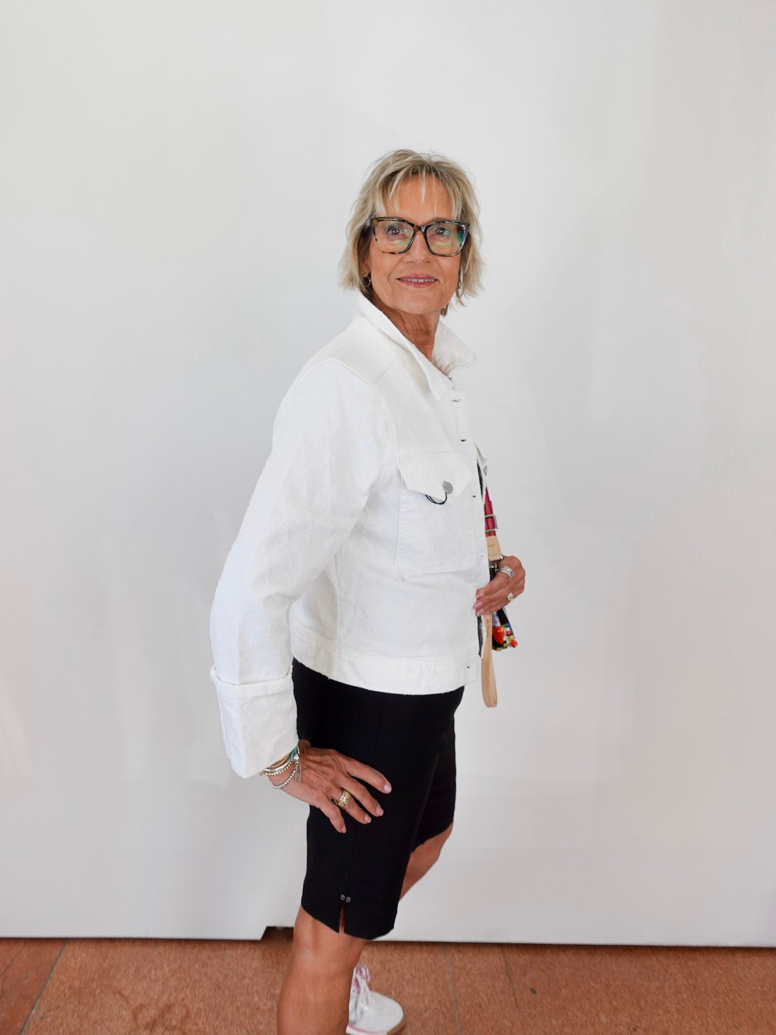Woman wearing a white jacket and black shorts against a plain background