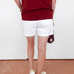 Person wearing a red top and white shorts with a white background