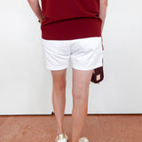Person wearing a red top and white shorts with a white background