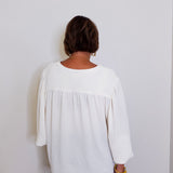 Person wearing a white blouse against a plain background
