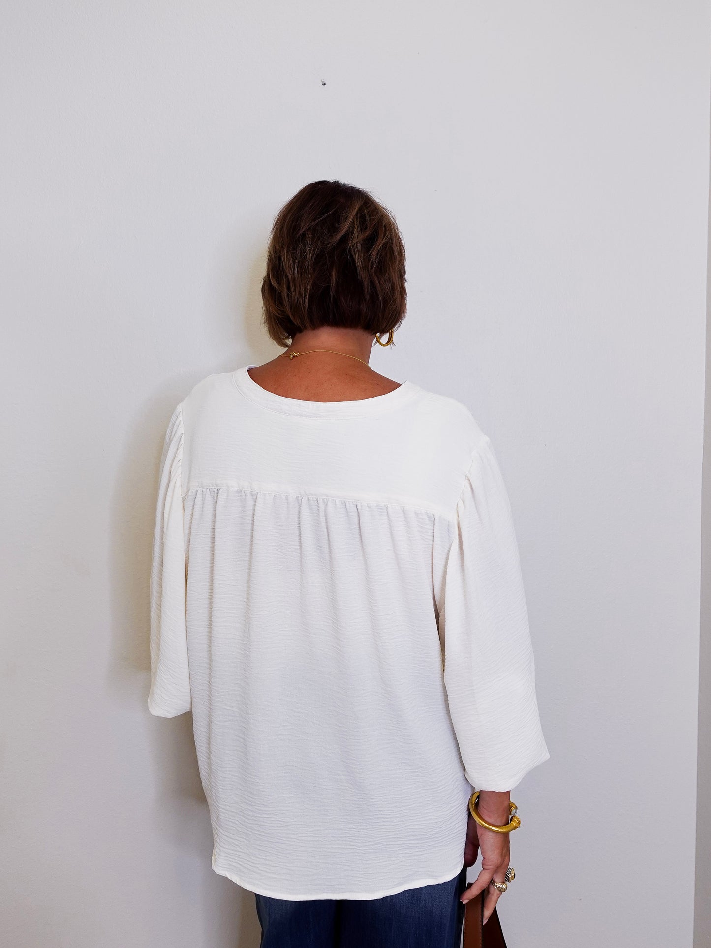 Person wearing a white blouse against a plain background
