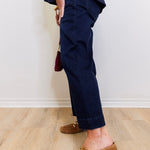 Person wearing navy pants and brown loafers on a light wooden floor.
