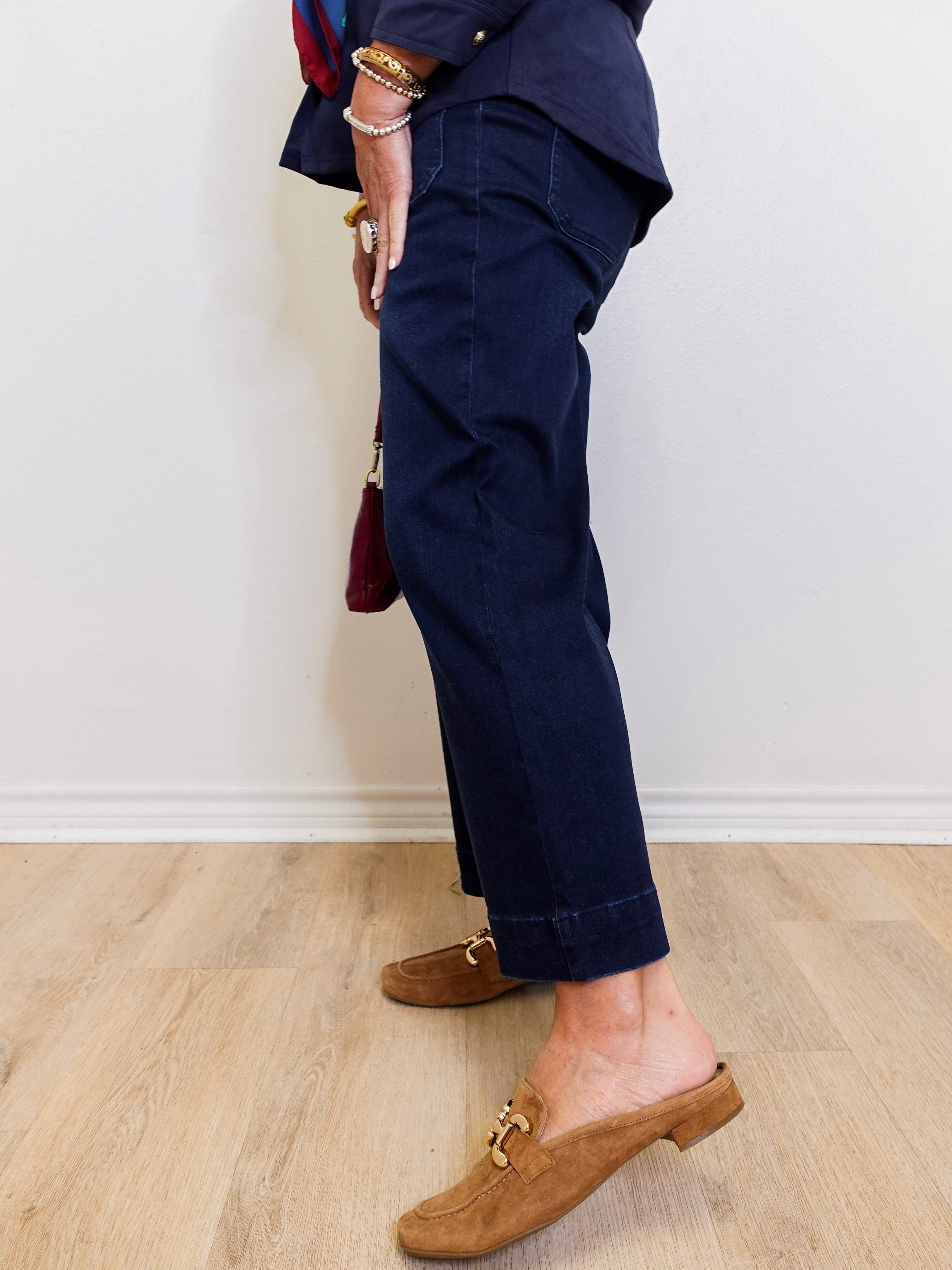 Person wearing navy pants and brown loafers on a light wooden floor.